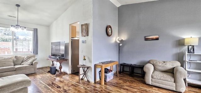 living area with vaulted ceiling, visible vents, and wood finished floors