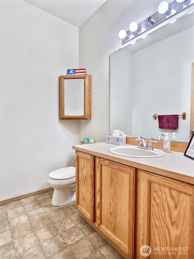 half bath with vanity, toilet, and baseboards