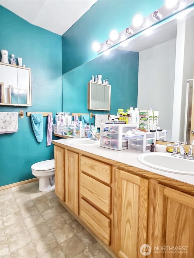 full bath featuring double vanity, toilet, and a sink