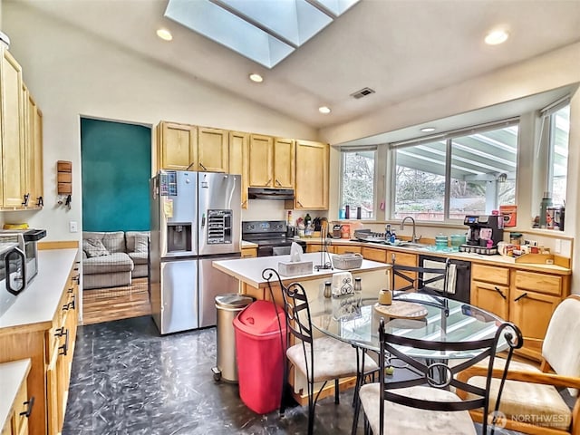 kitchen with visible vents, under cabinet range hood, light countertops, vaulted ceiling with skylight, and black appliances