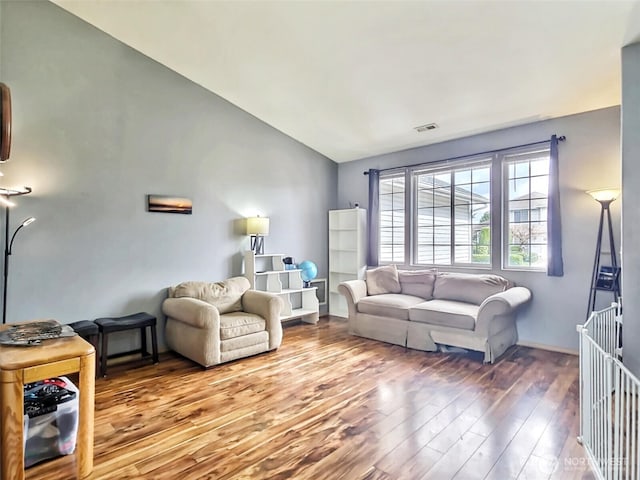 living room featuring visible vents, lofted ceiling, and wood finished floors