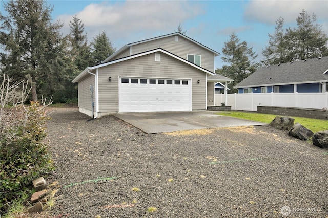 garage featuring gravel driveway and fence