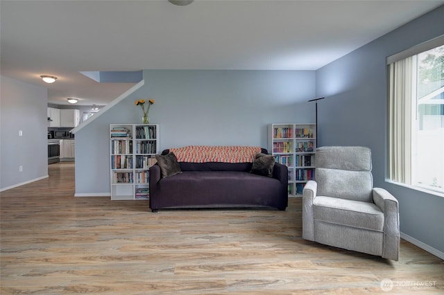 living area with light wood-style flooring, baseboards, and a wealth of natural light