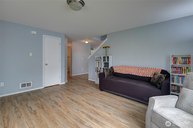 living area with wood finished floors, visible vents, and baseboards