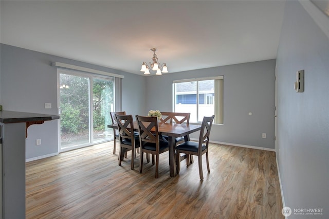 dining area featuring baseboards, light wood-style floors, and a chandelier