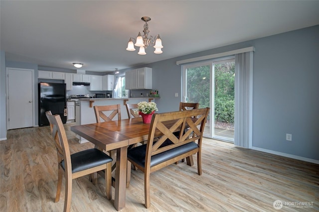 dining space with a notable chandelier, light wood-style floors, and baseboards