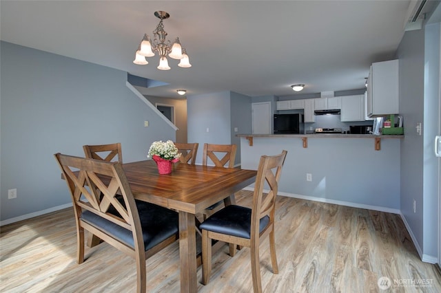 dining room featuring a chandelier, light wood finished floors, and baseboards