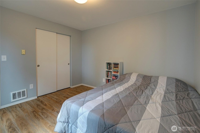 bedroom with visible vents, baseboards, and wood finished floors