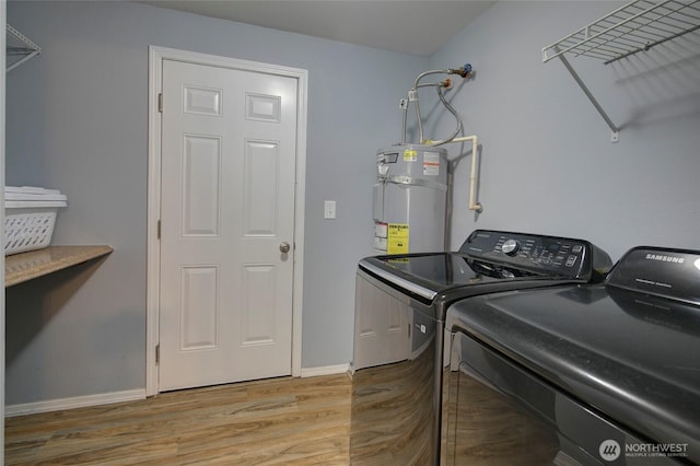 clothes washing area featuring light wood finished floors, baseboards, water heater, laundry area, and washer and dryer