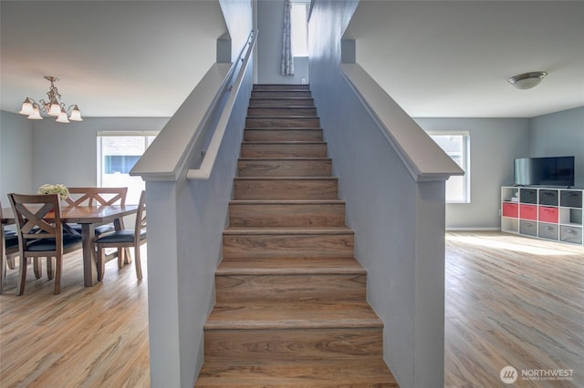 staircase featuring a notable chandelier and wood finished floors