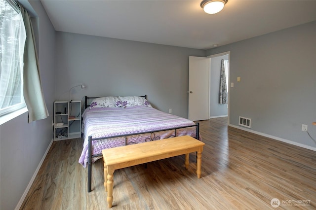 bedroom featuring light wood-type flooring, visible vents, and baseboards