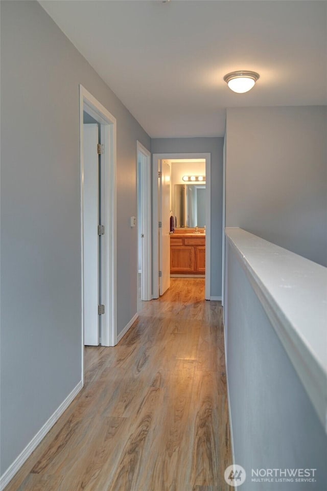 hallway featuring baseboards and light wood finished floors