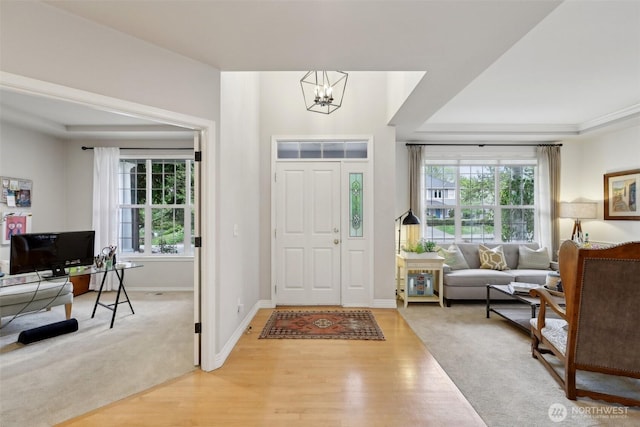 foyer entrance featuring baseboards, light wood-type flooring, and a notable chandelier