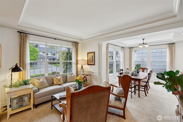 living area featuring a wealth of natural light, a tray ceiling, and light carpet