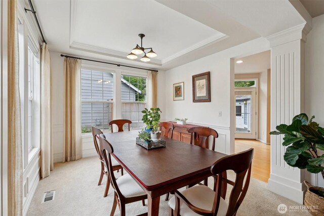 dining room with visible vents, an inviting chandelier, ornate columns, light colored carpet, and a tray ceiling
