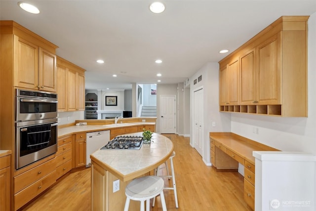 kitchen with recessed lighting, appliances with stainless steel finishes, light wood-style flooring, and a peninsula