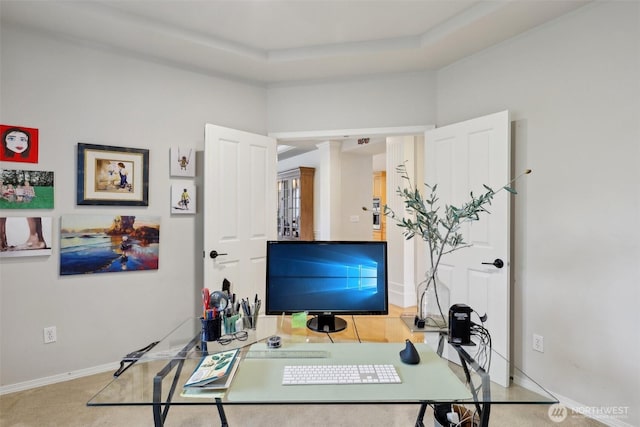 home office with baseboards and a raised ceiling