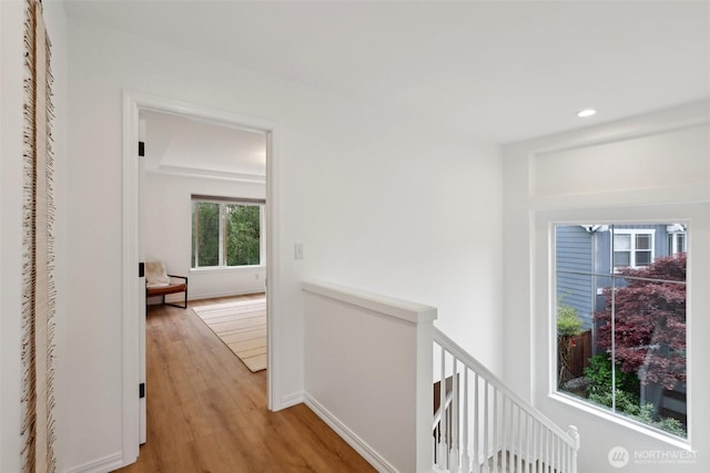 corridor featuring light wood-type flooring, recessed lighting, baseboards, and an upstairs landing