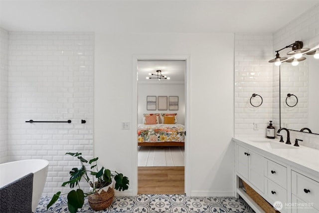 full bath featuring a soaking tub, baseboards, ensuite bathroom, and vanity
