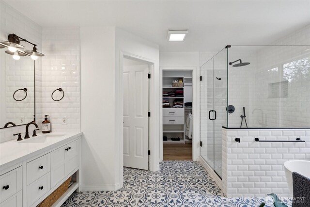 full bath with vanity, a walk in closet, tile patterned flooring, and a shower stall