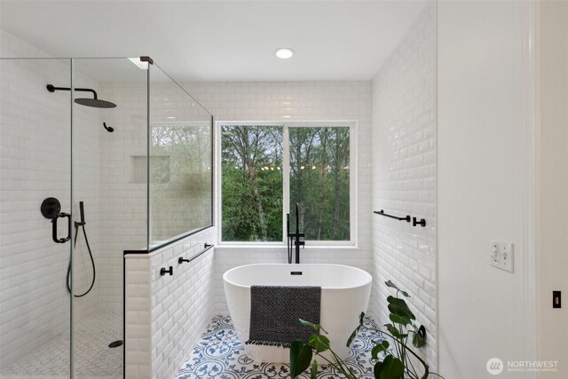 bathroom featuring tile patterned floors, a freestanding tub, a shower stall, and tile walls