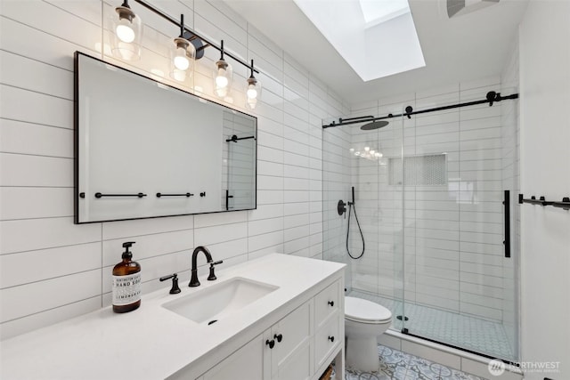 full bathroom featuring vanity, toilet, tile walls, a shower stall, and a skylight