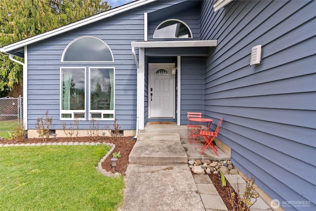 doorway to property with a lawn and fence