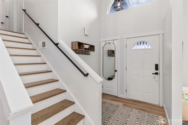foyer featuring stairway, wood finished floors, and a towering ceiling