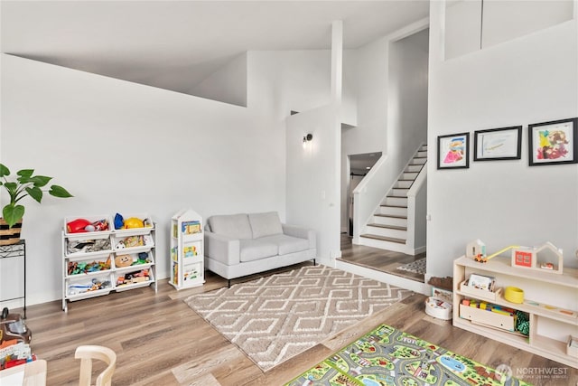 playroom featuring high vaulted ceiling and wood finished floors