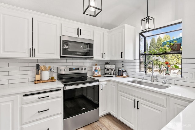 kitchen with white cabinetry, backsplash, appliances with stainless steel finishes, and a sink