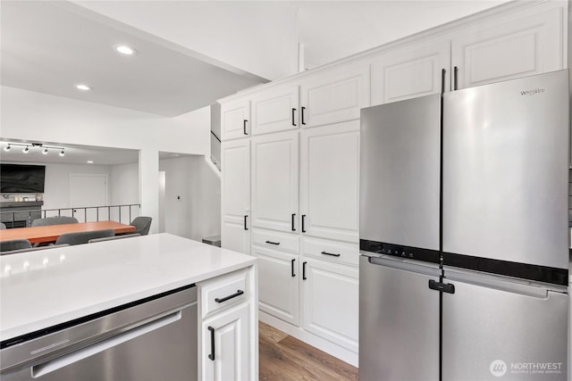 kitchen with light wood finished floors, recessed lighting, stainless steel appliances, light countertops, and white cabinets