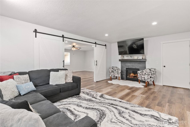 living area with recessed lighting, a barn door, a textured ceiling, and wood finished floors