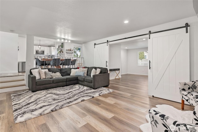 living area featuring recessed lighting, light wood-style flooring, baseboards, and a barn door