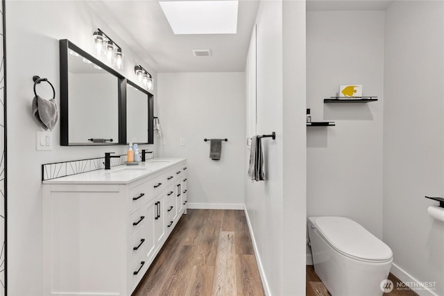 bathroom with wood finished floors, visible vents, baseboards, double vanity, and toilet