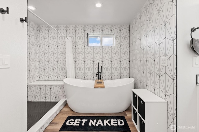 bathroom with a tile shower, recessed lighting, a freestanding bath, and tile walls