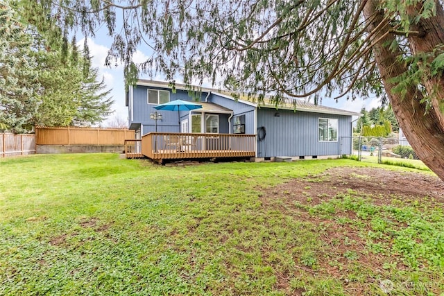 rear view of property featuring a deck, a lawn, and a fenced backyard