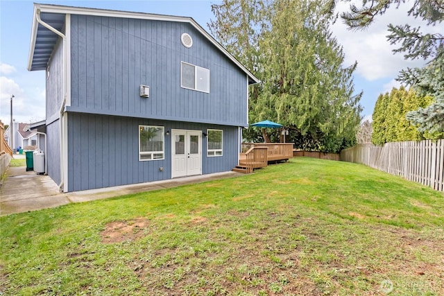 back of house featuring a lawn, a wooden deck, and a fenced backyard