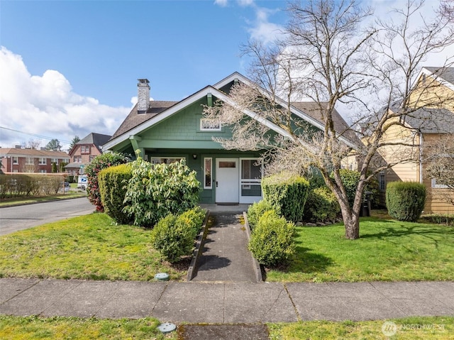 view of front of house with a porch, a chimney, and a front lawn