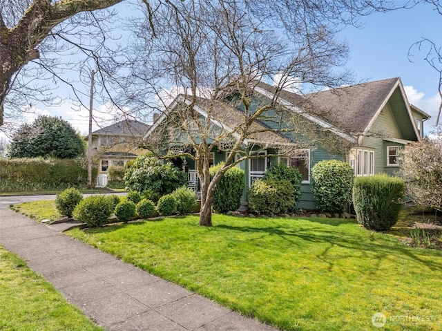 view of front of house featuring a front lawn and roof with shingles