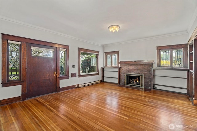 unfurnished living room featuring wood finished floors, baseboards, ornamental molding, a brick fireplace, and baseboard heating