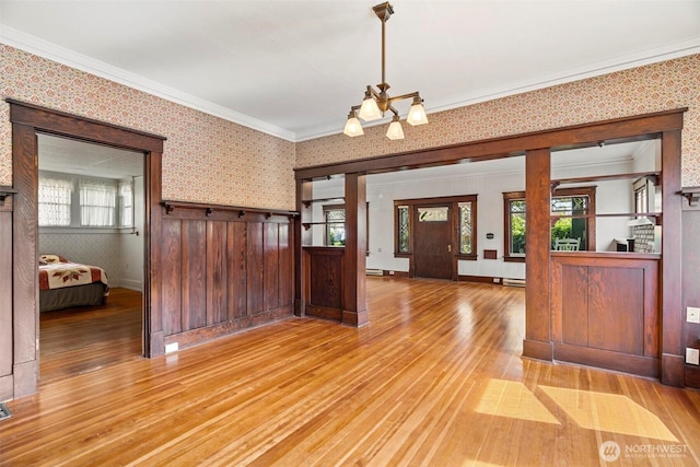 foyer with light wood finished floors, plenty of natural light, crown molding, and wallpapered walls