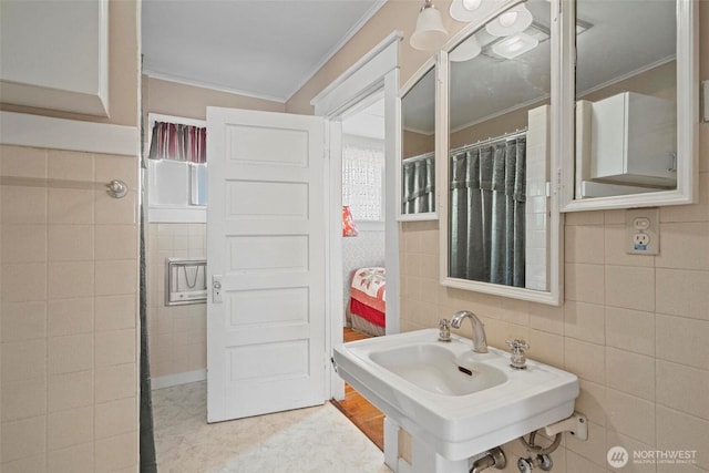 full bath featuring a sink, plenty of natural light, tile walls, and ornamental molding