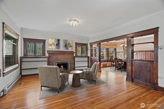 living area with visible vents, ornamental molding, a fireplace, an inviting chandelier, and wood finished floors