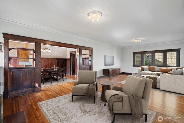 living area featuring wood finished floors, a chandelier, and ornamental molding
