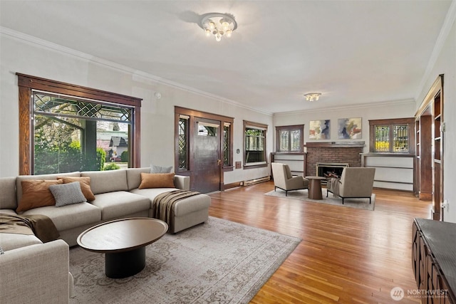 living area featuring light wood-style flooring, plenty of natural light, a fireplace, and a baseboard radiator