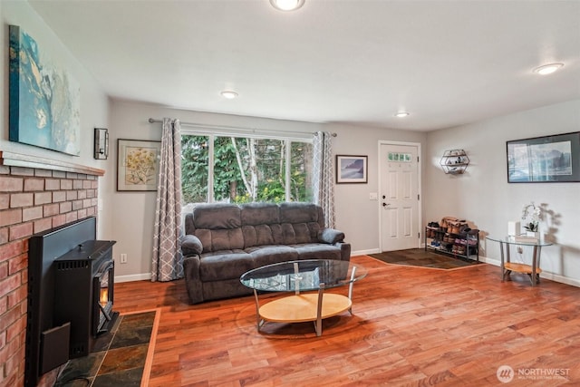 living room featuring baseboards, a brick fireplace, recessed lighting, and wood finished floors