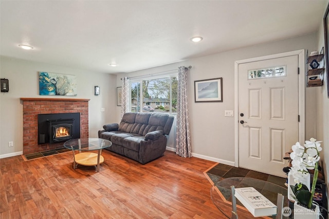 living area with wood finished floors, baseboards, and a brick fireplace