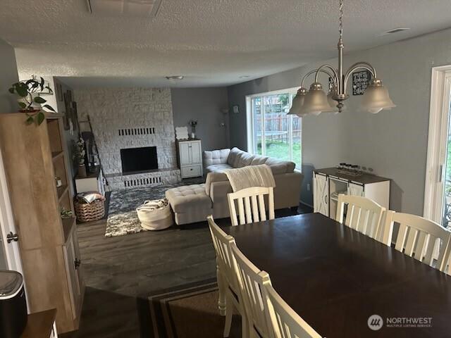 310 Kosmos Ln, Morton, WA 98356 - dining space with visible vents, a large fireplace, a textured ceiling, and wood finished floors