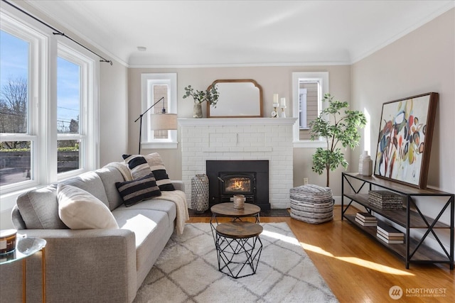 living area featuring ornamental molding, a brick fireplace, and wood finished floors