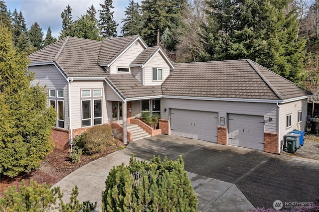 view of front of home with concrete driveway, a tiled roof, brick siding, and a garage